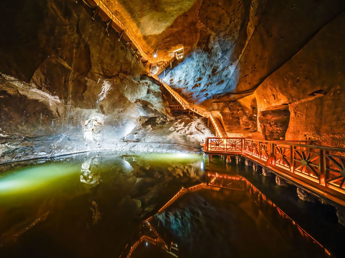 Underground salt chamber with glowing chandeliers and reflections on the floor.