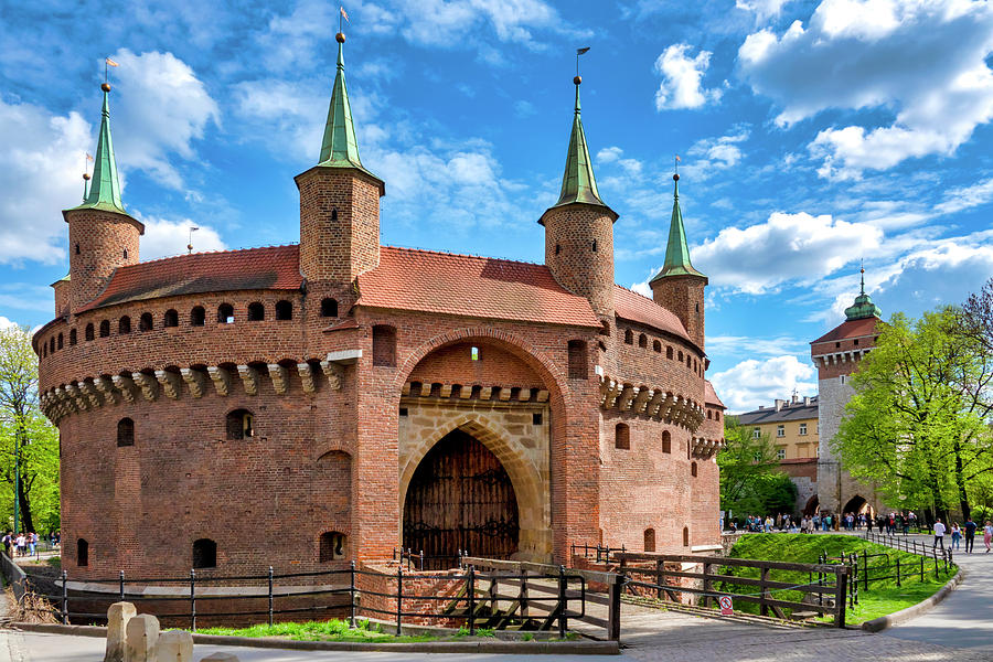 Street perspective toward St. Florian’s Gate with morning light and few tourists.