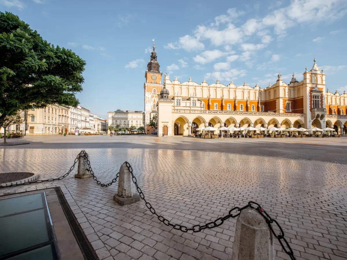 Sunset view of Kraków’s Main Square with St. Mary’s Basilica and horse carriages.